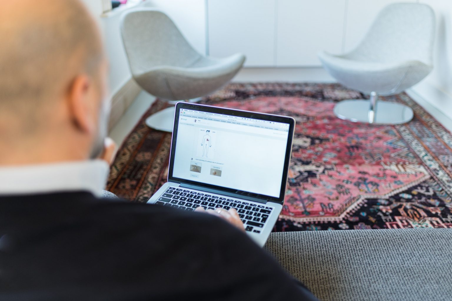 Huisdokter die aan zijn laptop zit.