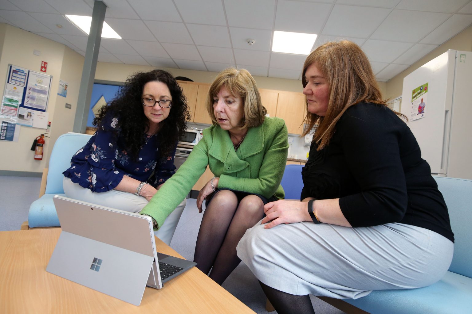 three women gathered around a Microsoft Surface