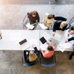 the image looks down on 7 people having a meeting