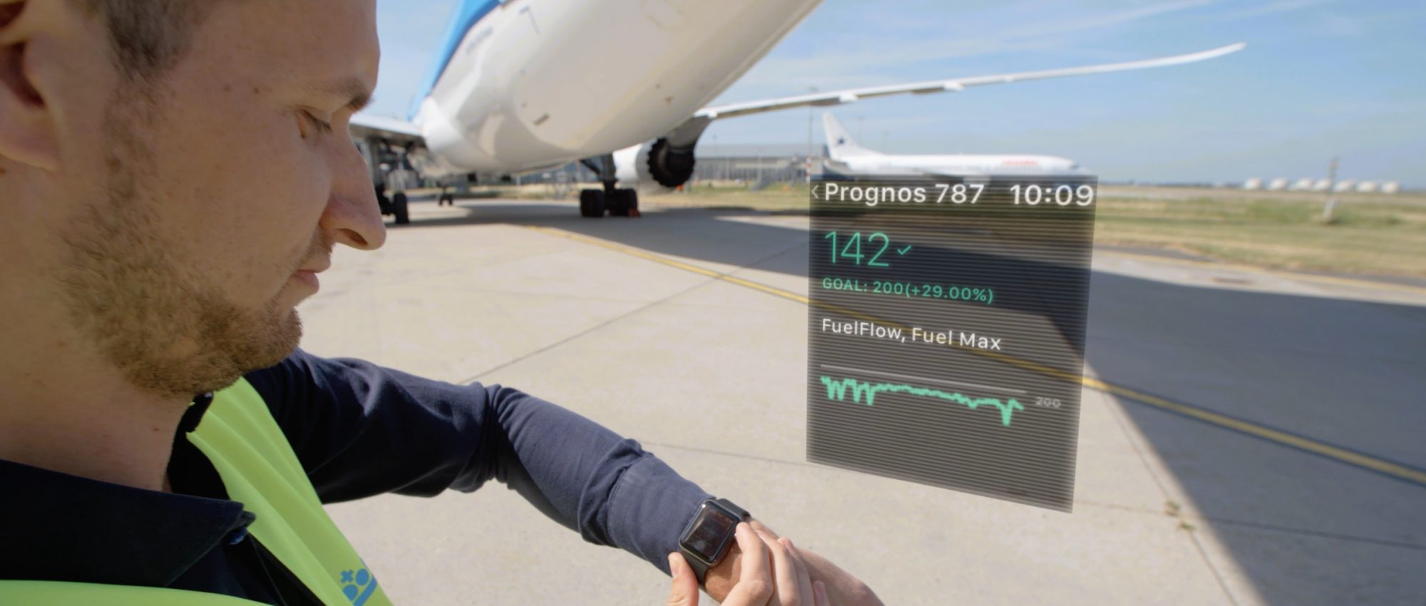 Guy standing next to plane looking at Smartwatch to check reporting.