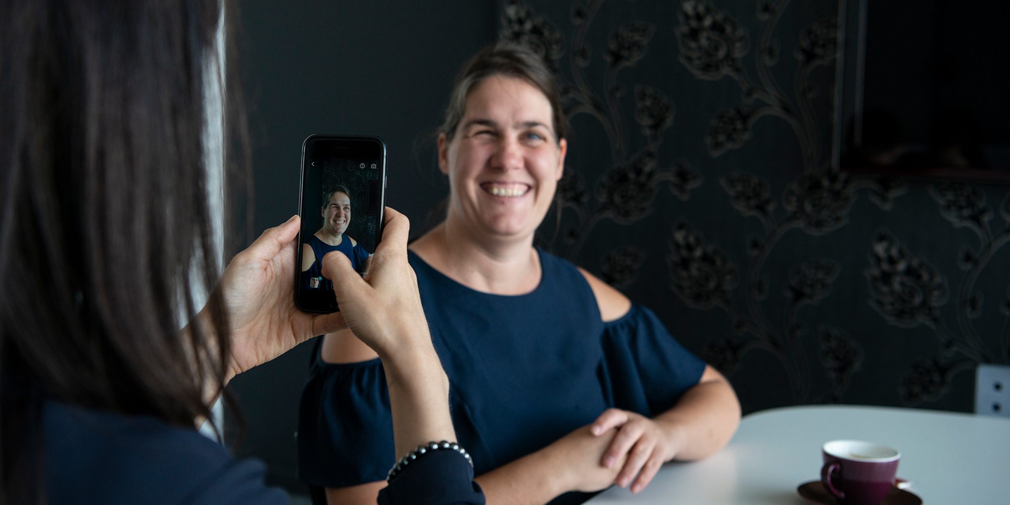Katrien neemt een foto met een smartphone van een glimlachende Monique
