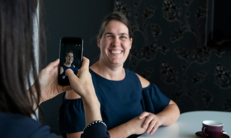 Katrien neemt een foto met een smartphone van een glimlachende Monique