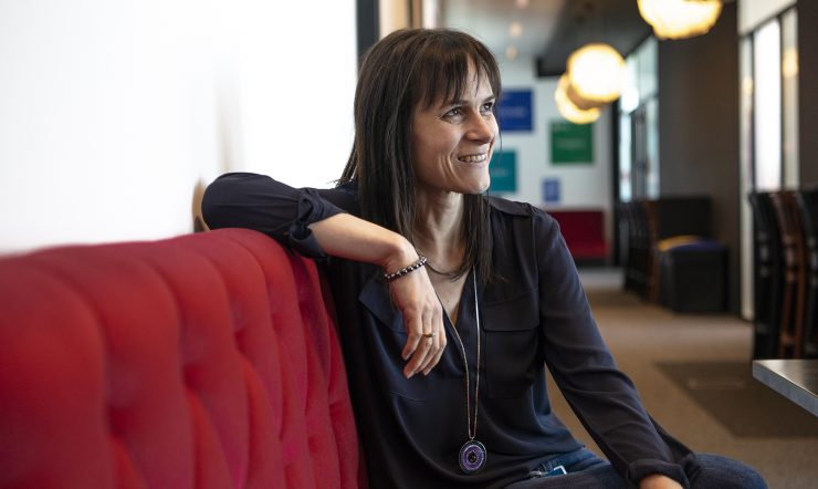 Katrien De Graeve, installée dans un fauteuil, regarde à sa gauche tout en souriant