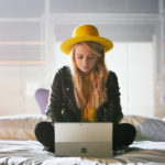 A woman with a yellow hat working on a Surface