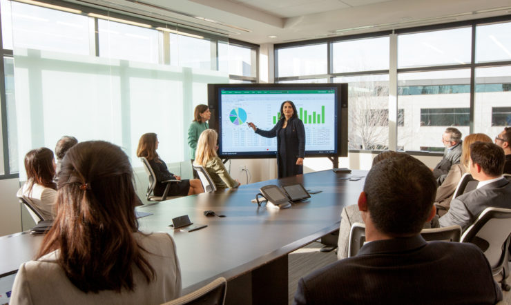 Um grupo de pessoas assistem a uma apresentação numa sala de reuniões