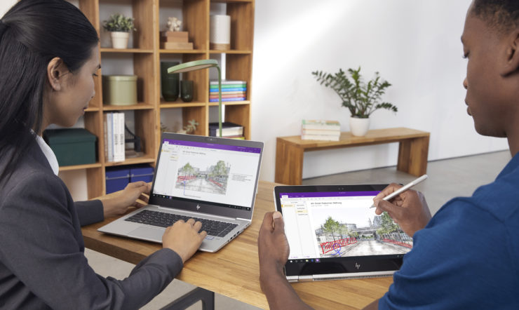 Duas pessoas a trabalharem colaborativamente em dois computadores