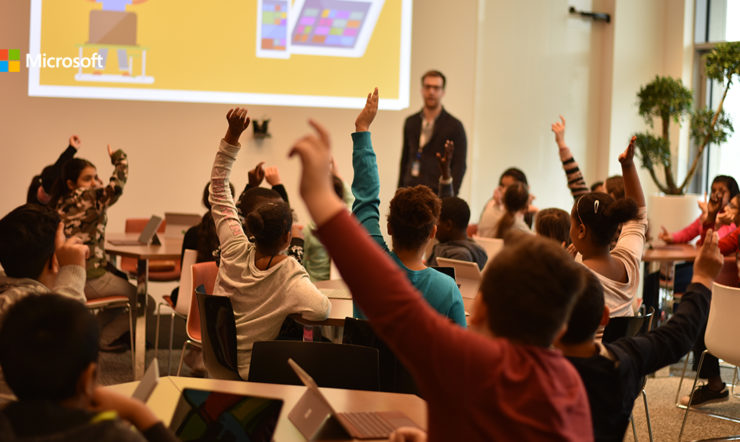 Een groep kinderen die een vinger omhoog steken om antwoord te geven aan de leraar.