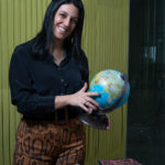 Uma mulher sorridente a agarrar num globo terrestre