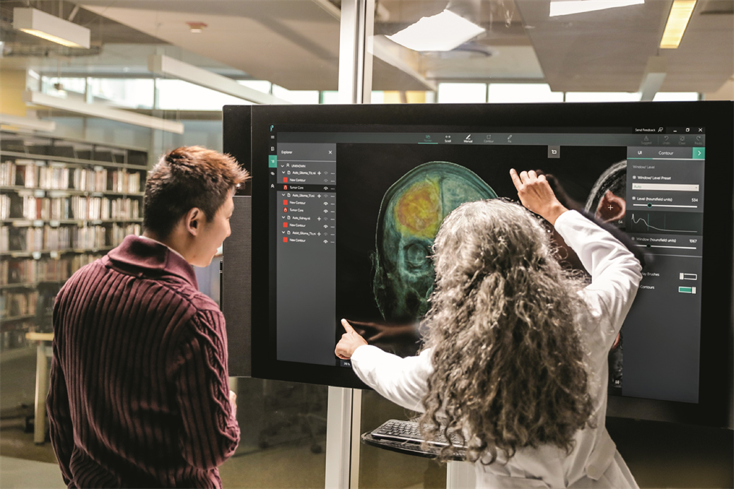 Duas pessoas analisam a imagem de um crânio humano no Microsoft Surface Hub