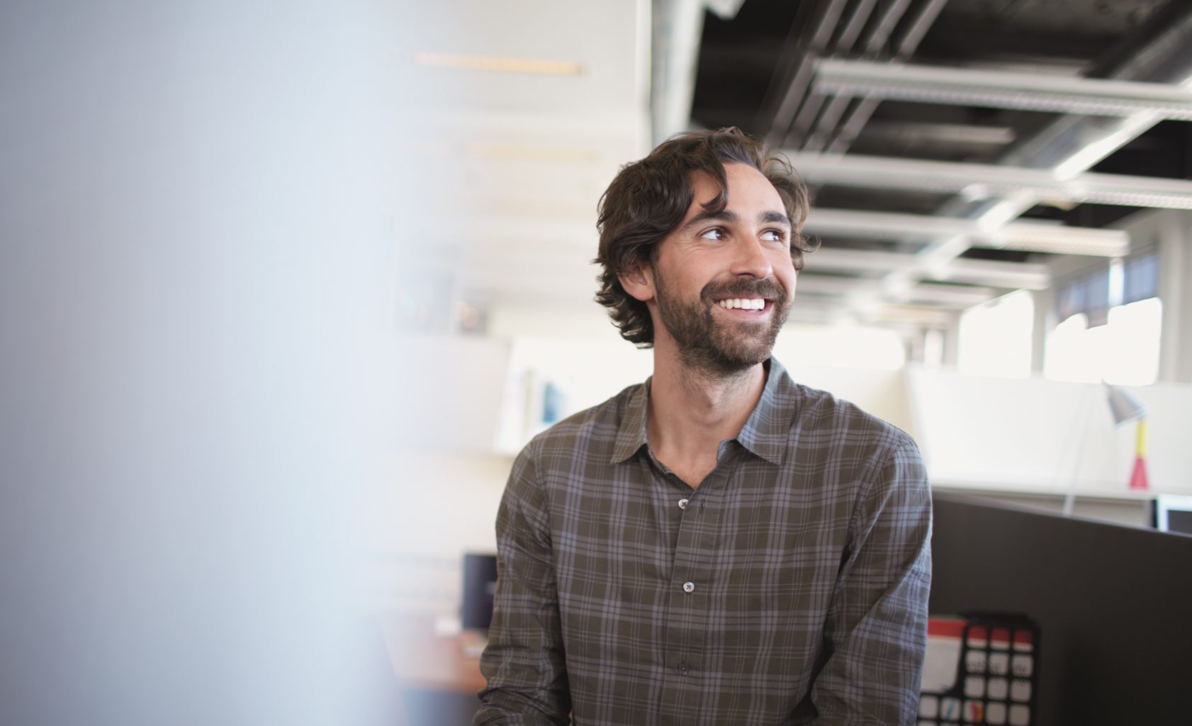 A smiling man wearing a gray shirt while looking up.