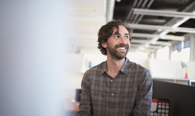 A smiling man wearing a gray shirt while looking up.