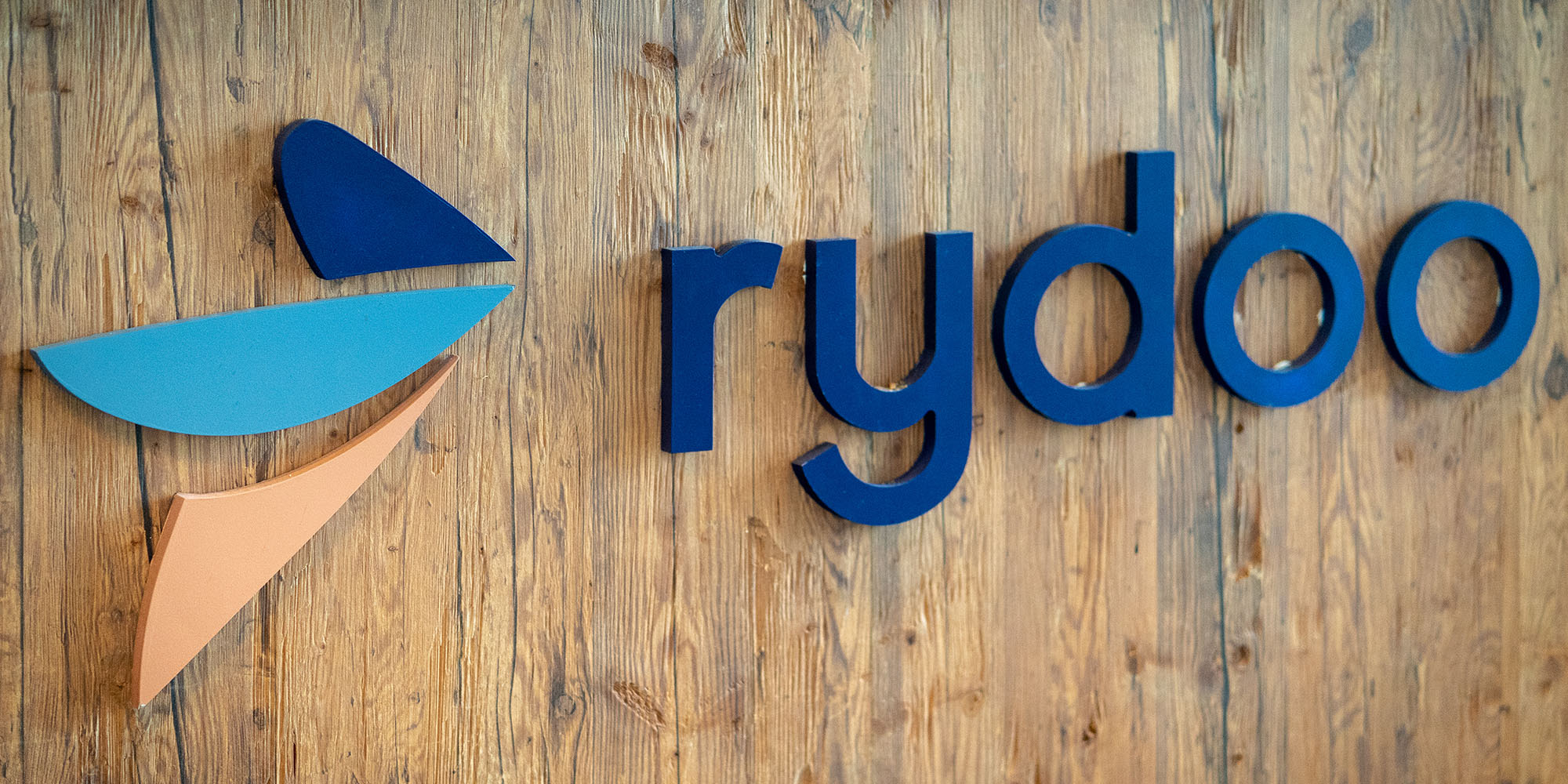 Rydoo-logo op houten wand.