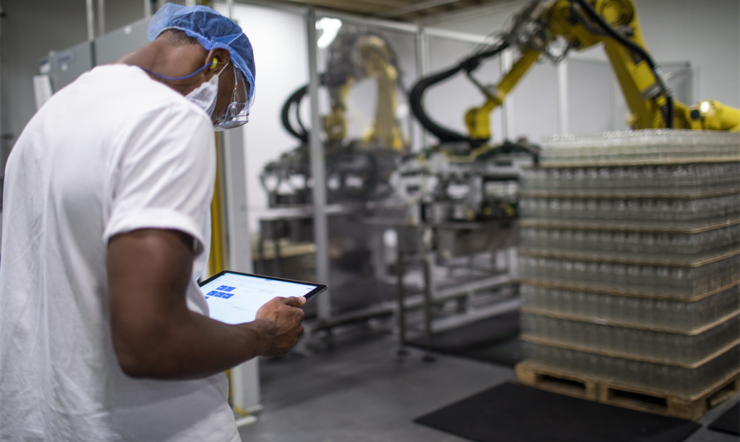 Um colaborador numa zona de carga a usar um tablet para controlar um robot a carregar paletes