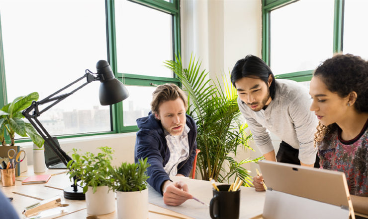 a man and a woman sitting at a table using a laptop computer