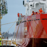 Een groot rood schip op de werf met een paar mannen aan boord