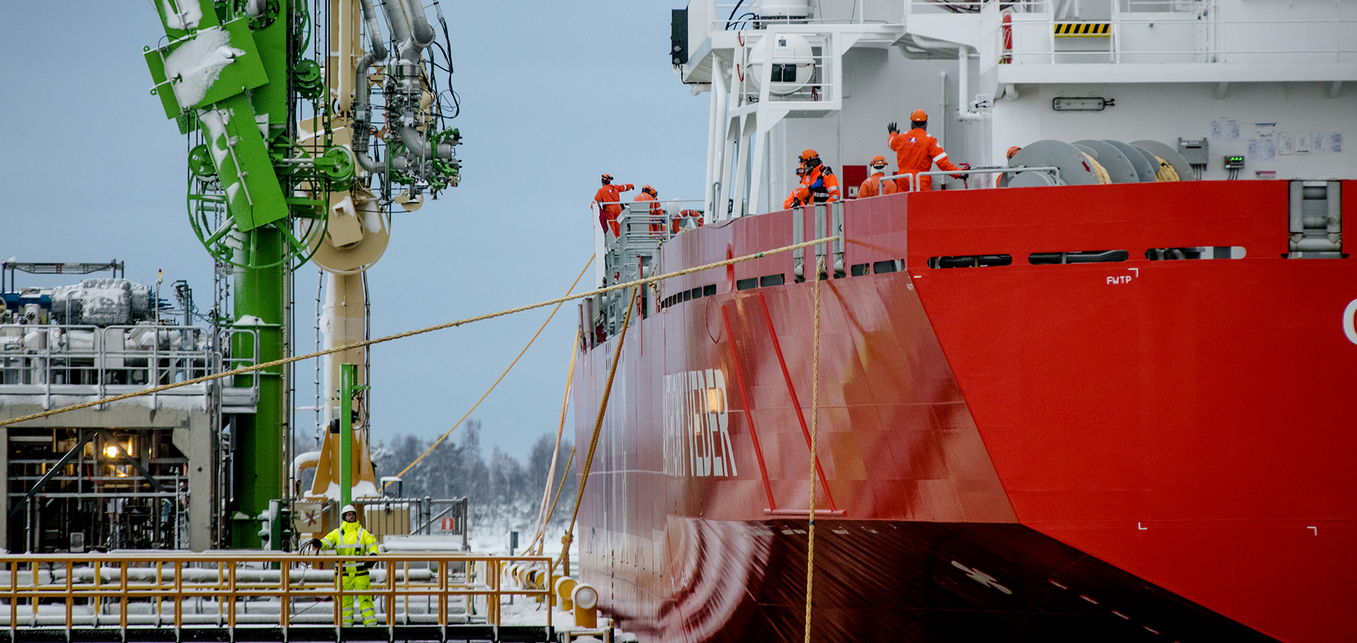 Un grand navire rouge avec quelques hommes à bord, stationnant dans un chantier naval.