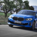 BMW bleue roulant sur une route dans un paysage montagneux.