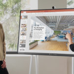 a man and a woman standing in front of a computer