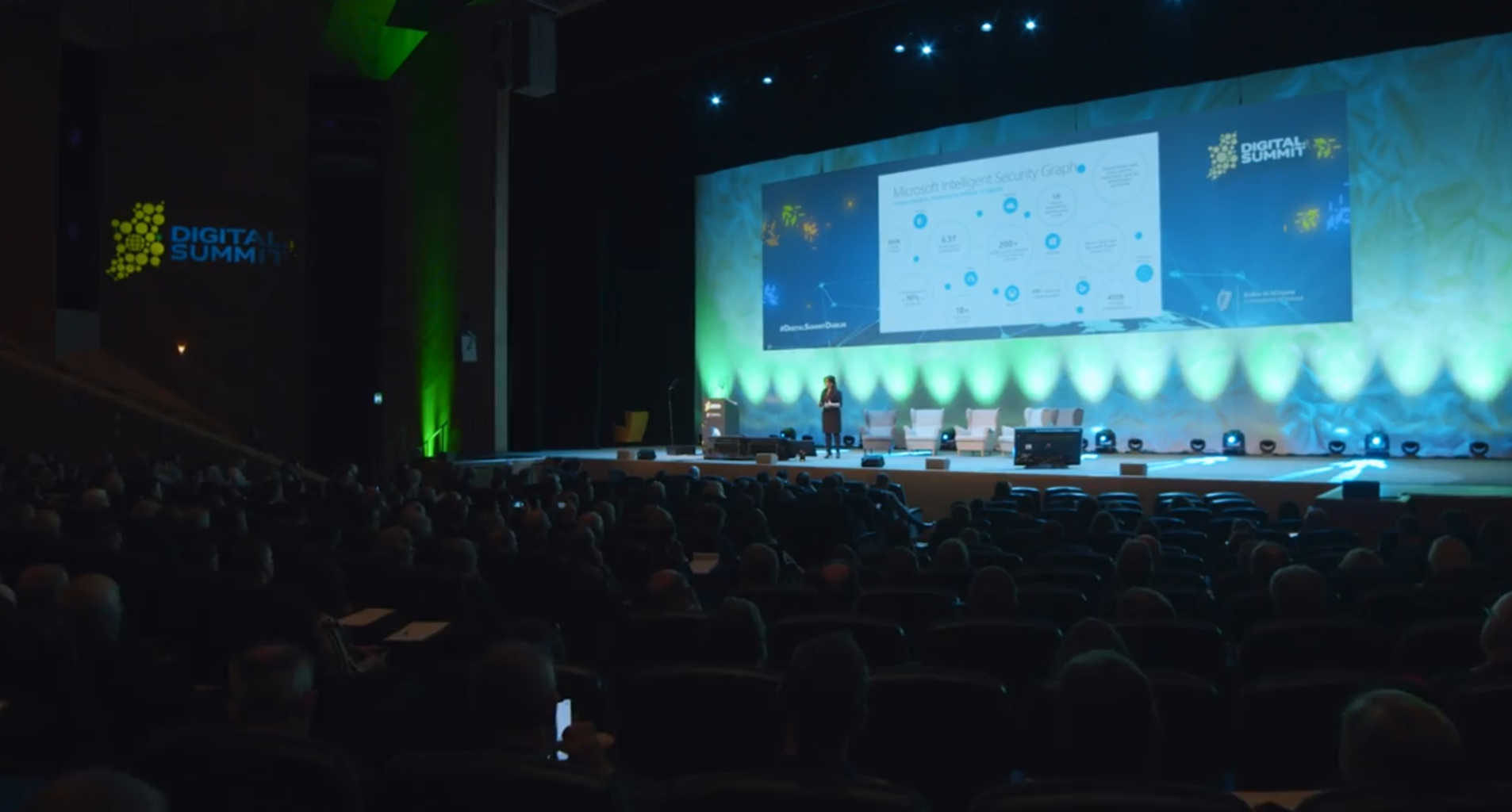 a crowd of people in a dark room listening to a presentation