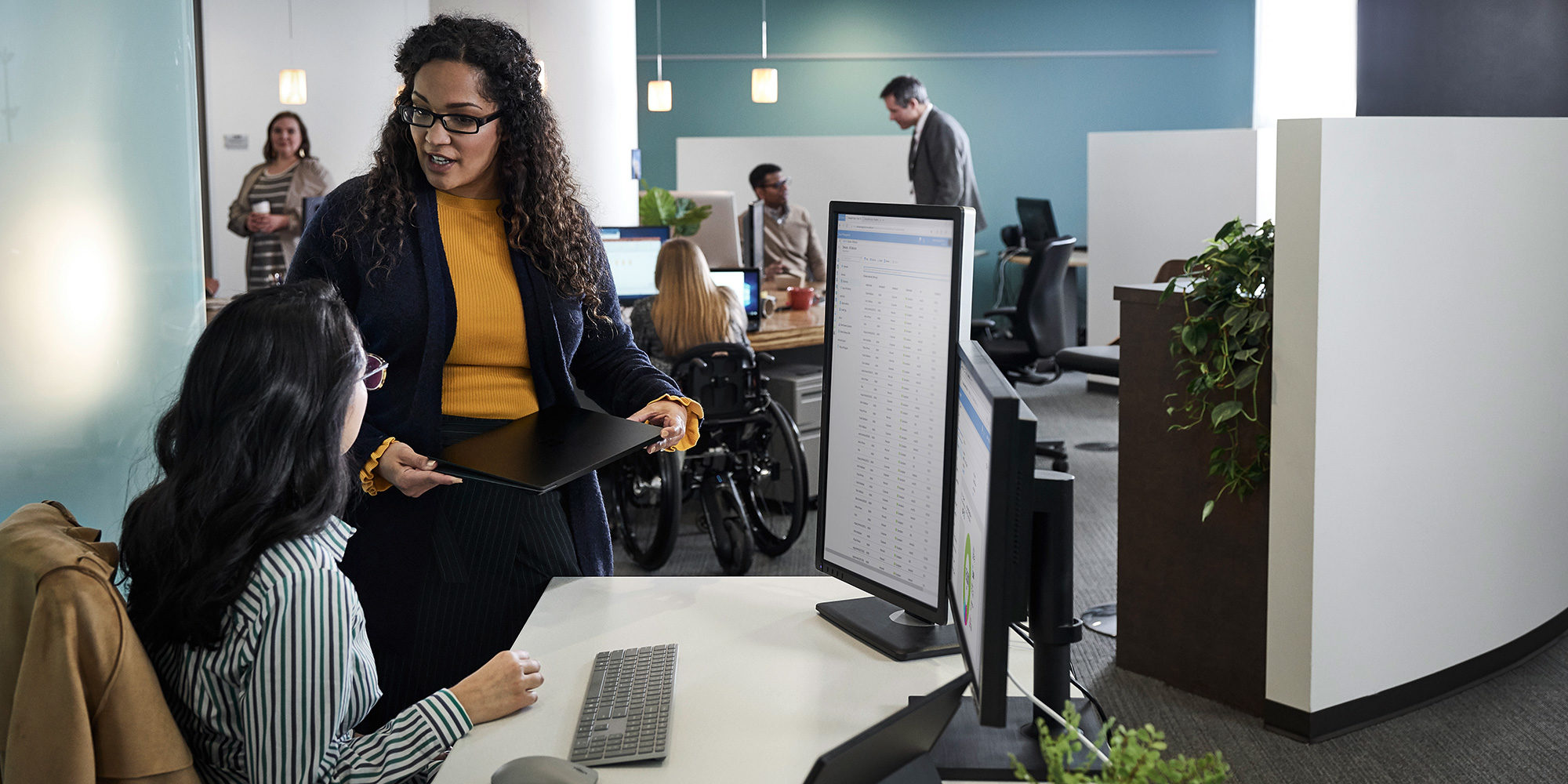 Two people sitting and standing in front of a computer