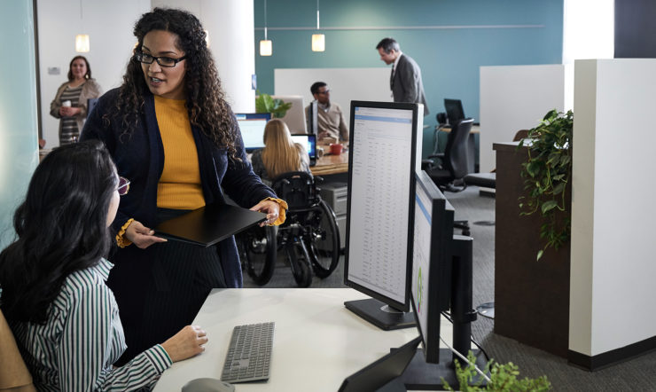 Two people sitting and standing in front of a computer