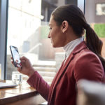 Eine Person, vor einem Fenster ein Telefon hält