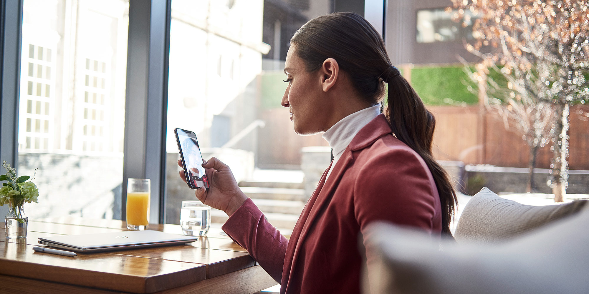 en person håller en telefon framför ett fönster