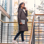 Vrouw met telefoon en Surface in een kantoorgebouw