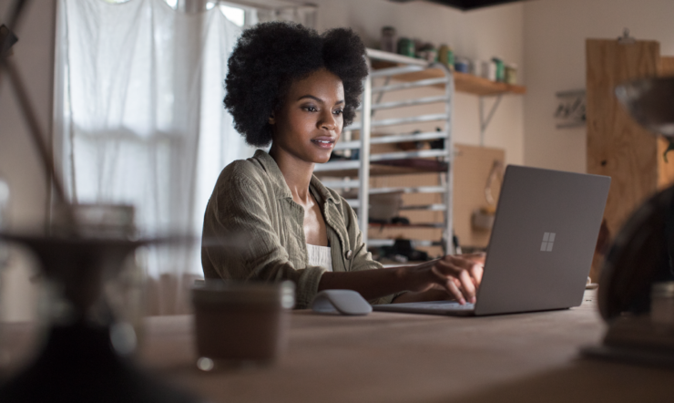 Female working on project using Microsoft Surface Laptop (platinum) in a ceramic workshop