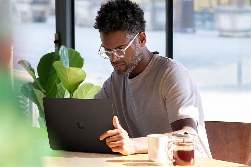 Contextual image of man working on black Surface Laptop 2 inside