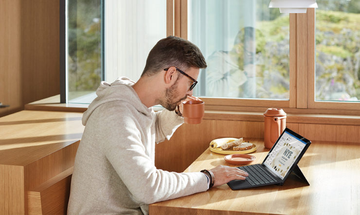 mies istuu pöydän ja edessä näpytellen tietokonetta
