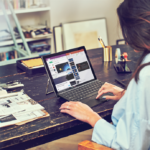 una persona sentada en una mesa usando una computadora portátil