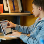 a man using a laptop computer sitting on top of a desk