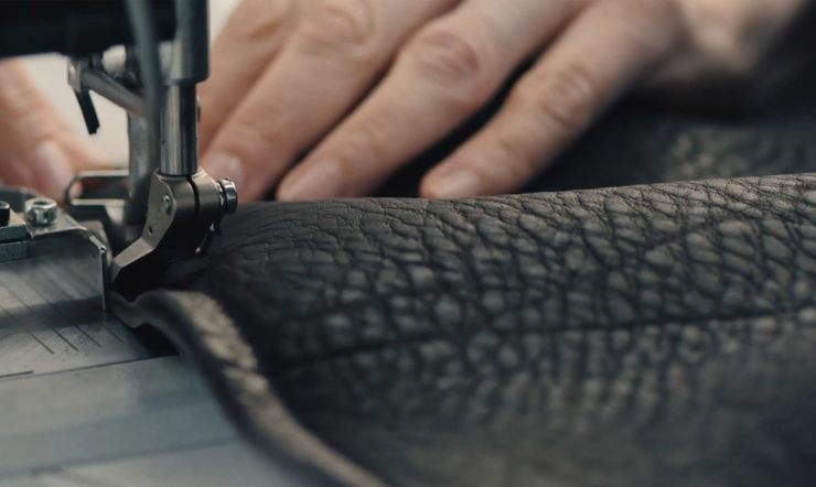 A close up of a hand sewing leather