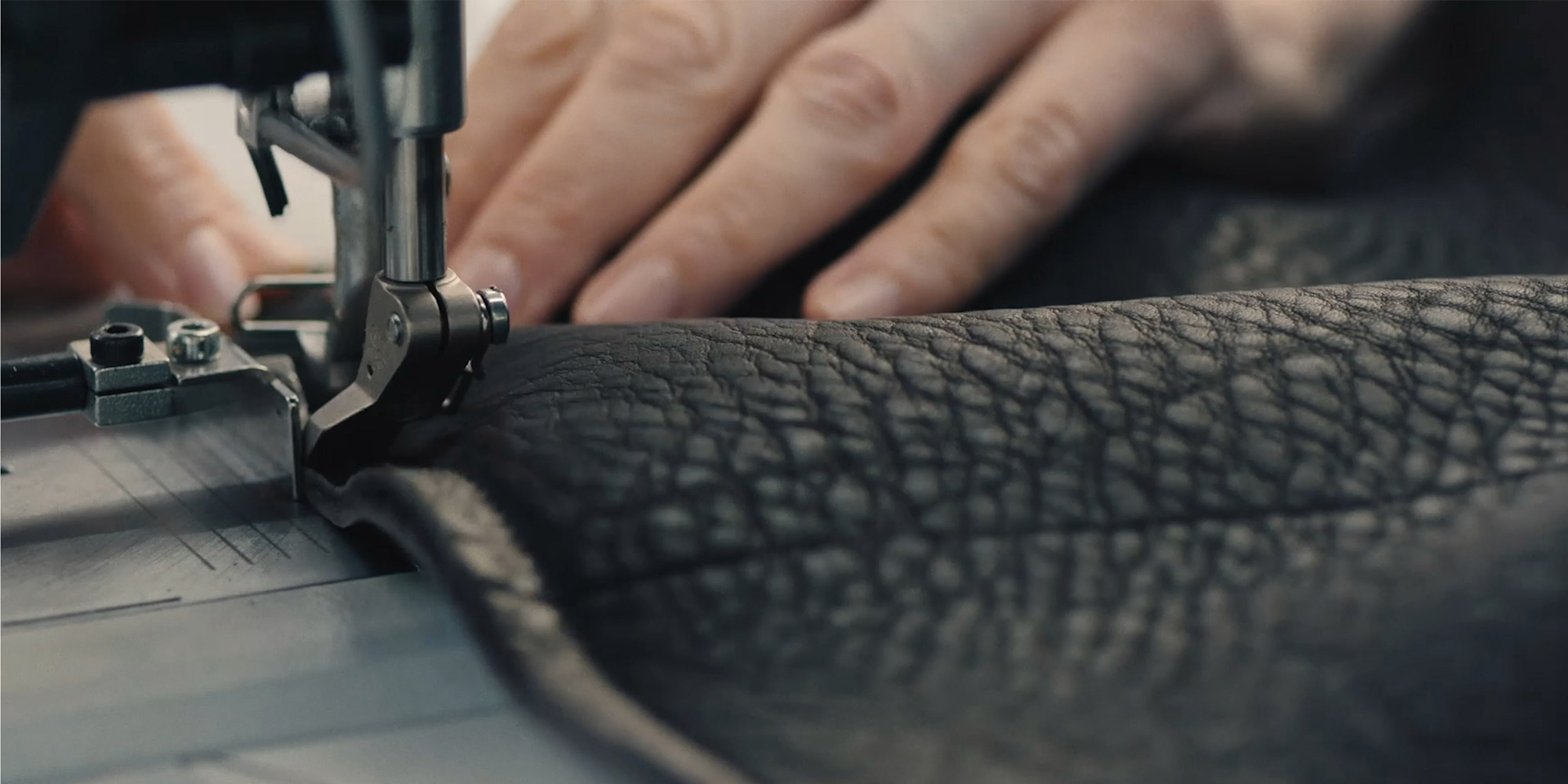 A close up of a hand sewing leather