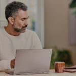 um homem em pé à frente de um computador portátil