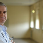 a doctor wearing a white coat and smiling at the camera