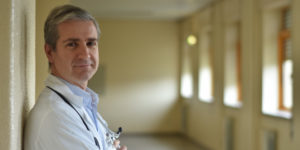 a doctor wearing a white coat and smiling at the camera