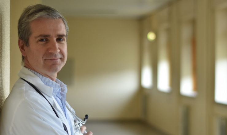 a doctor wearing a white coat and smiling at the camera