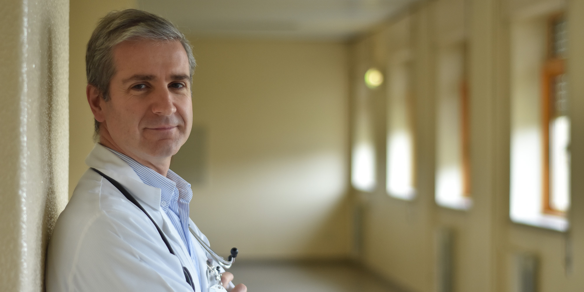 a doctor wearing a white coat and smiling at the camera