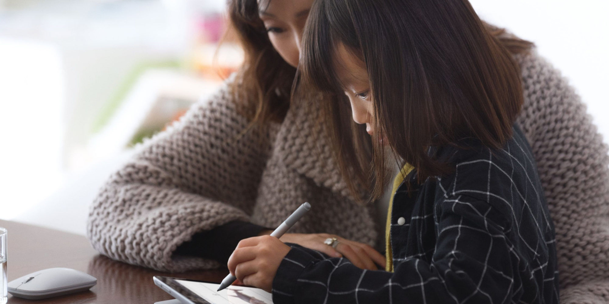 a woman and child sitting at a table using a laptop