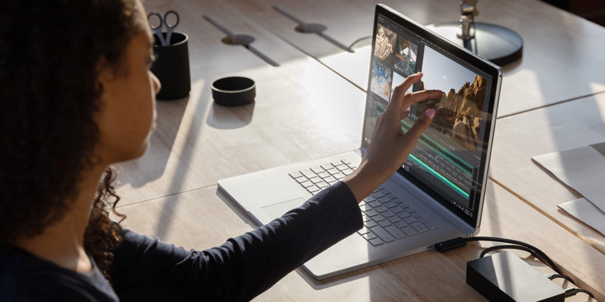 Eine Person sitzt an einem Tisch und arbeitet an einem Laptop.