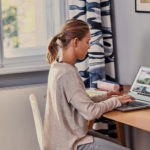 a person sitting at a table using a laptop