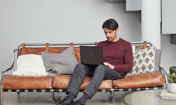 a person sitting on a sofa using a laptop