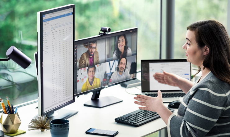 a woman sitting at a desk in front of a laptop computer in a virtual meeting