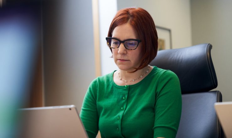 uma mulher sentada à mesa a utilizar um computador portátil