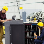 A male and female colleagues wearing helmets in a helicopter factory.