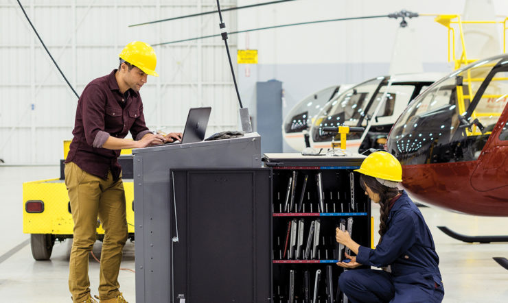 A male and female colleagues wearing helmets in a helicopter factory.