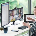 a person sitting at a desk in front of a laptop computer in a virtual meeting