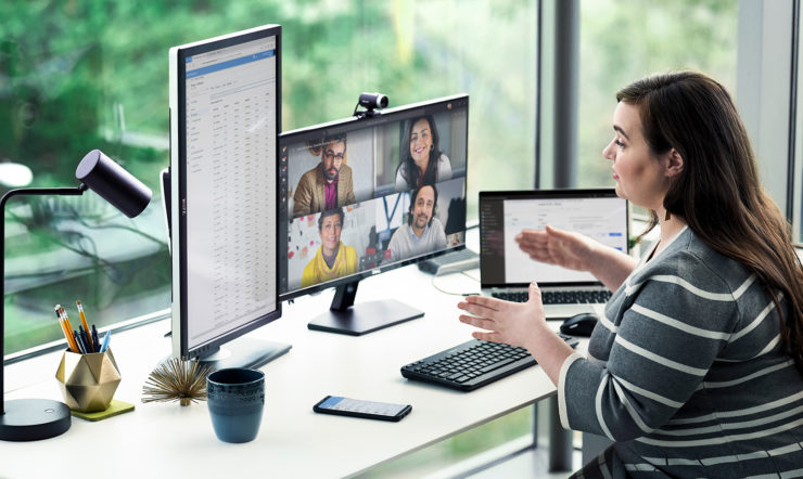 a person sitting at a desk in front of a laptop computer in a virtual meeting